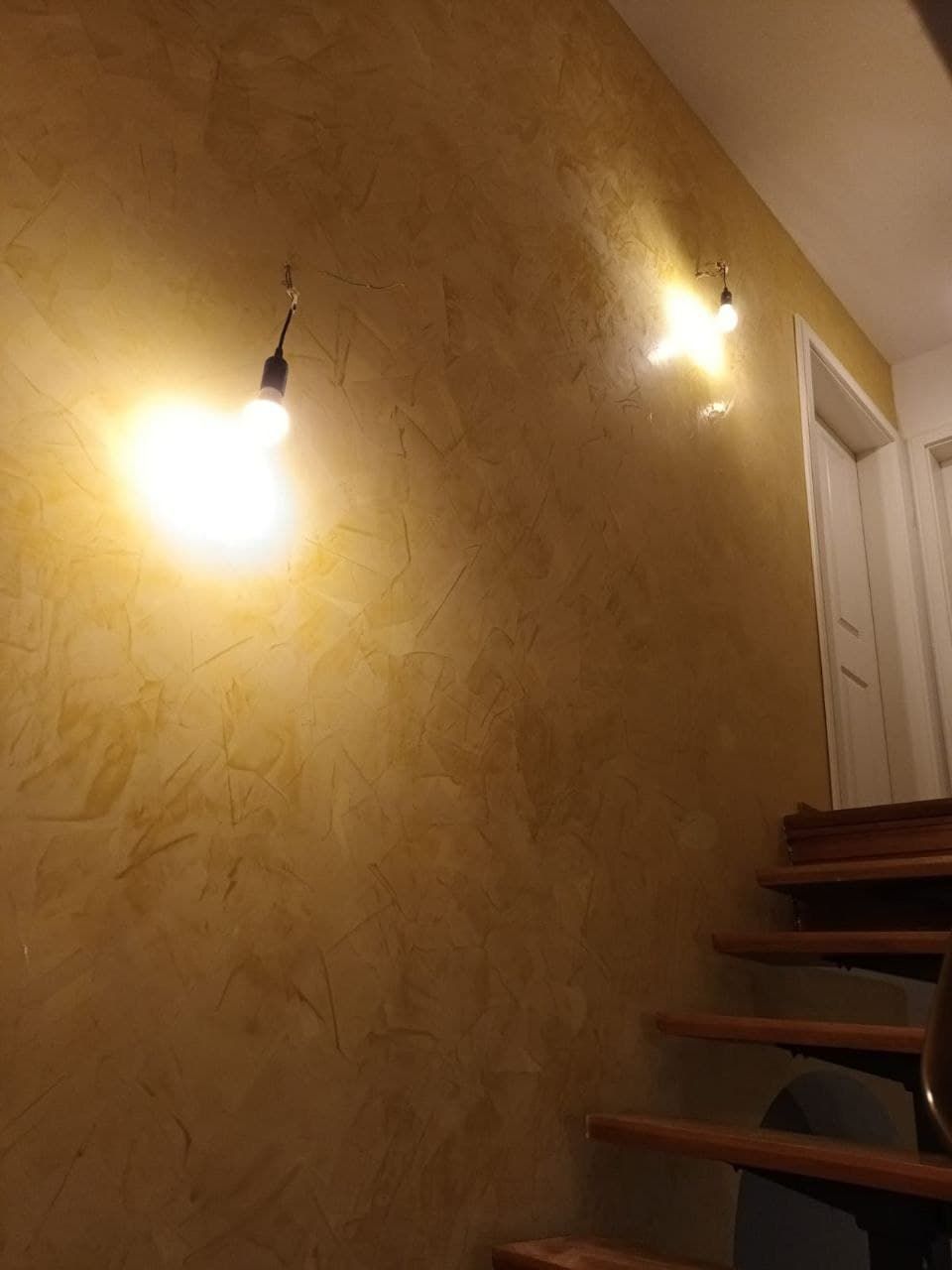 Warm goldene Wandfläche in Spachteltechnik, von zwei Wandlampen angeleuchtet.